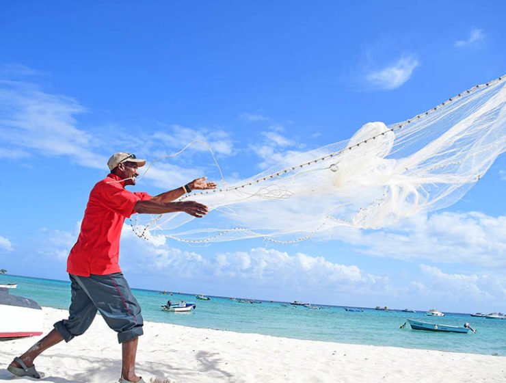Man Casting Fishing Net into Sea
