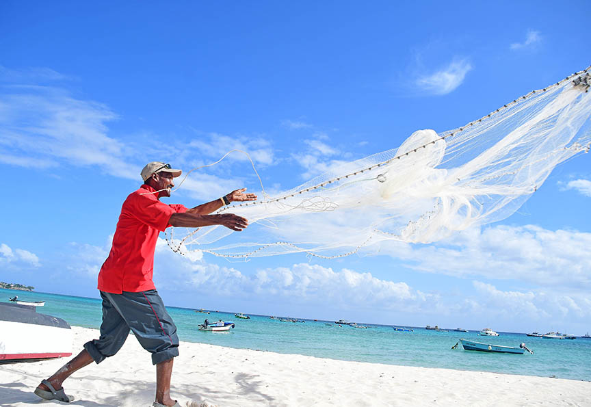 Man Casting Fishing Net into Sea